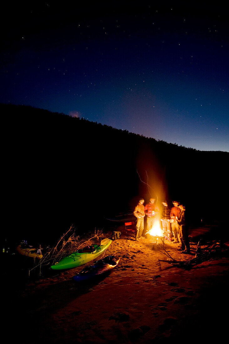 River runners huddle around the fire and swap stories during a winter river trip down the Salt River, AZ, AZ, USA