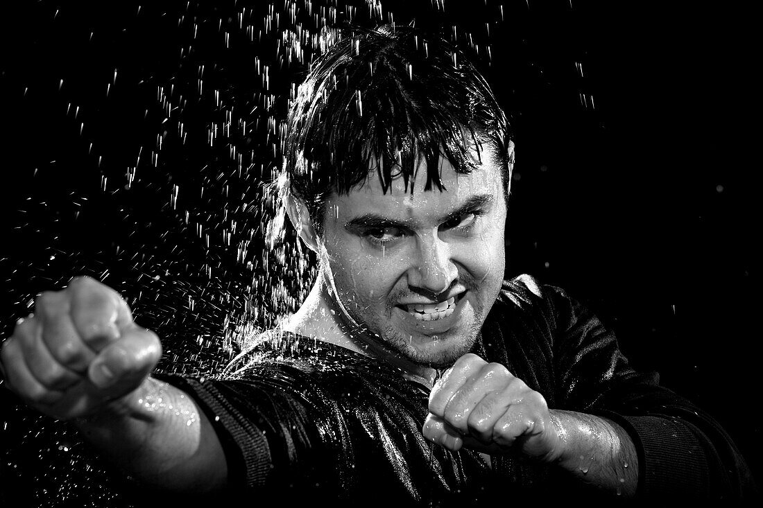 A young man wearing a jacket poses in a wushu stance while it rains down on him Camarillo, California, United States of America