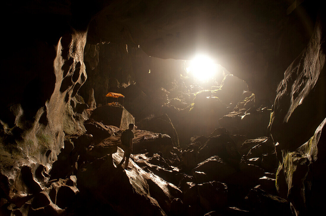 A traveler looking towards the light at the opening of a cave.  Vang Vieng, Laos, Asia Vang Vieng, Vientiane, laos