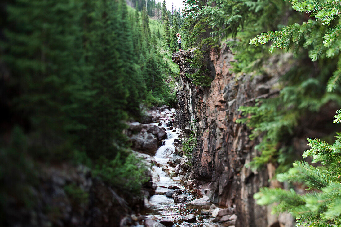 Young woman hiking enjoys the view of lush forest and beautiful river Vail, Colorado, USA