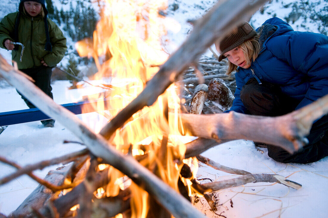 Two brothers start a campfire in the backcountry of California Sierra, CA, USA