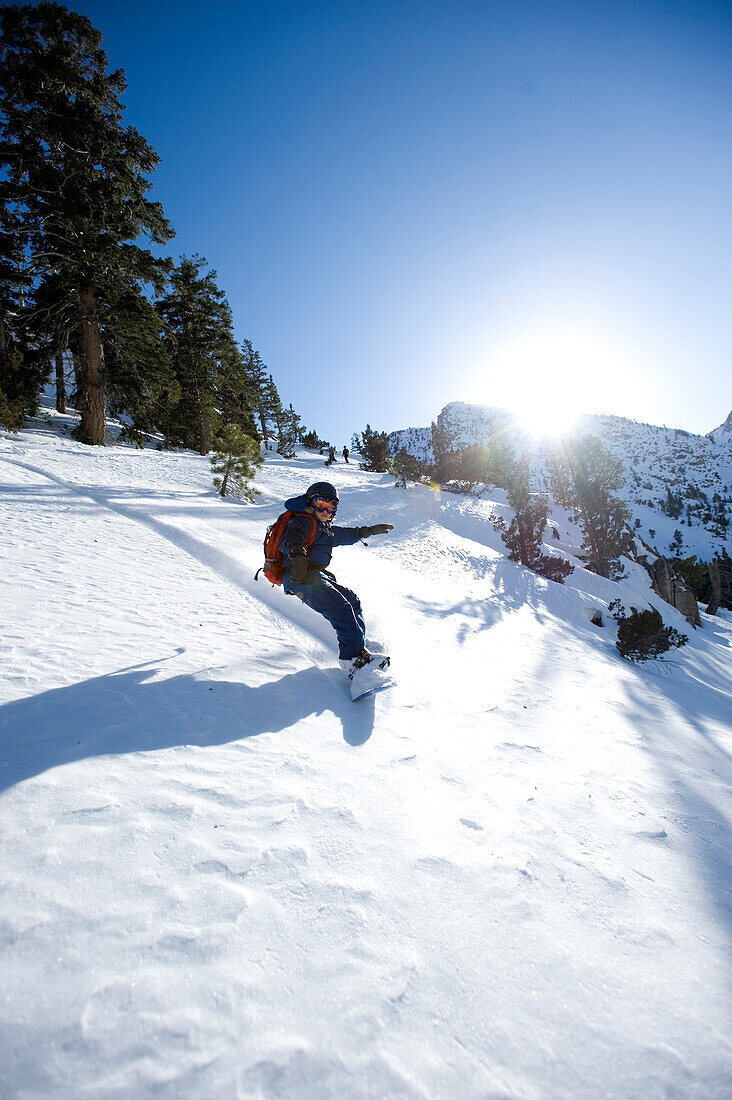 A boy snowboarding in the California backcountry Sierra, CA, USA