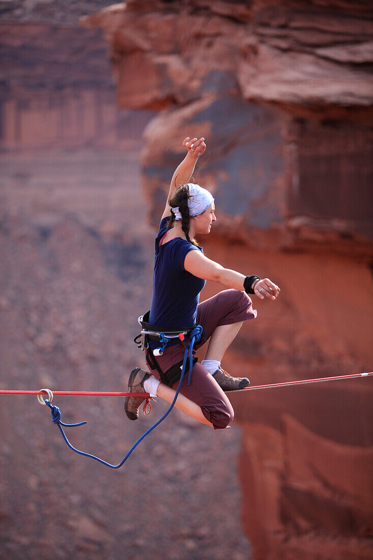 A female highliner poses on a highline at the Fruit Bowl in Moab, Utah, USA Moab, Utah, United States