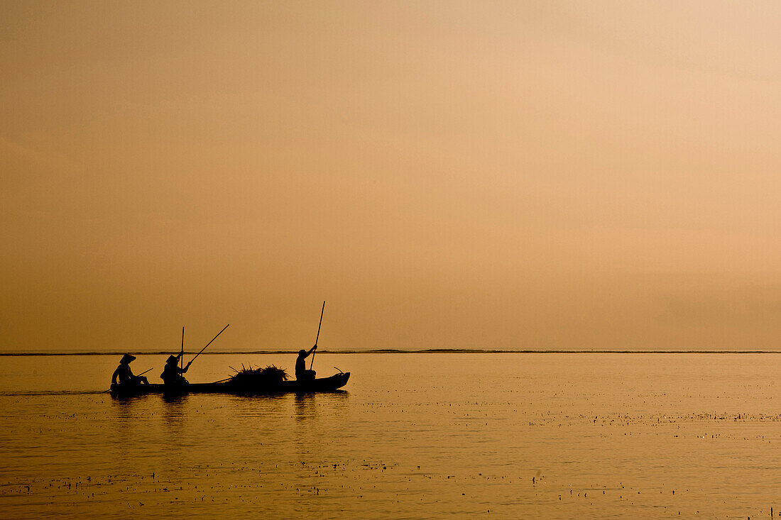 Silhouettes of fisherman poling their boat in Bali, Indonesia Sanur, Bali, Indonesia