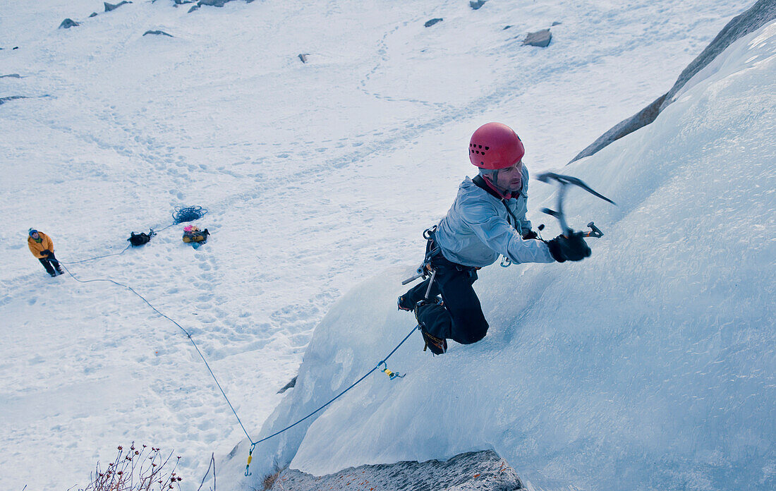 A man finds the perfect spot to place an ice axe while ice climbing in Lee Vining, California Lee Vining, California, USA