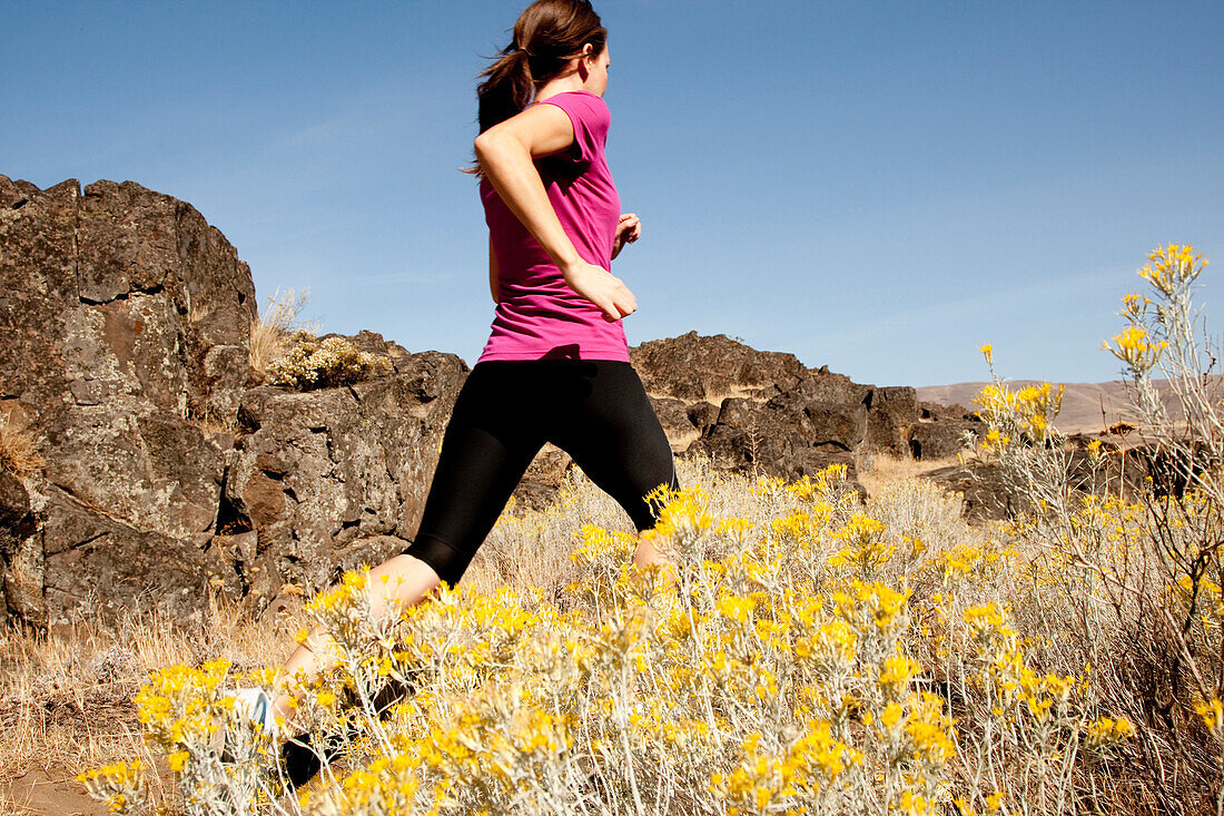 An athletic woman jogging in the Columbia Gorge, Oregon Hood River, Oregon, USA