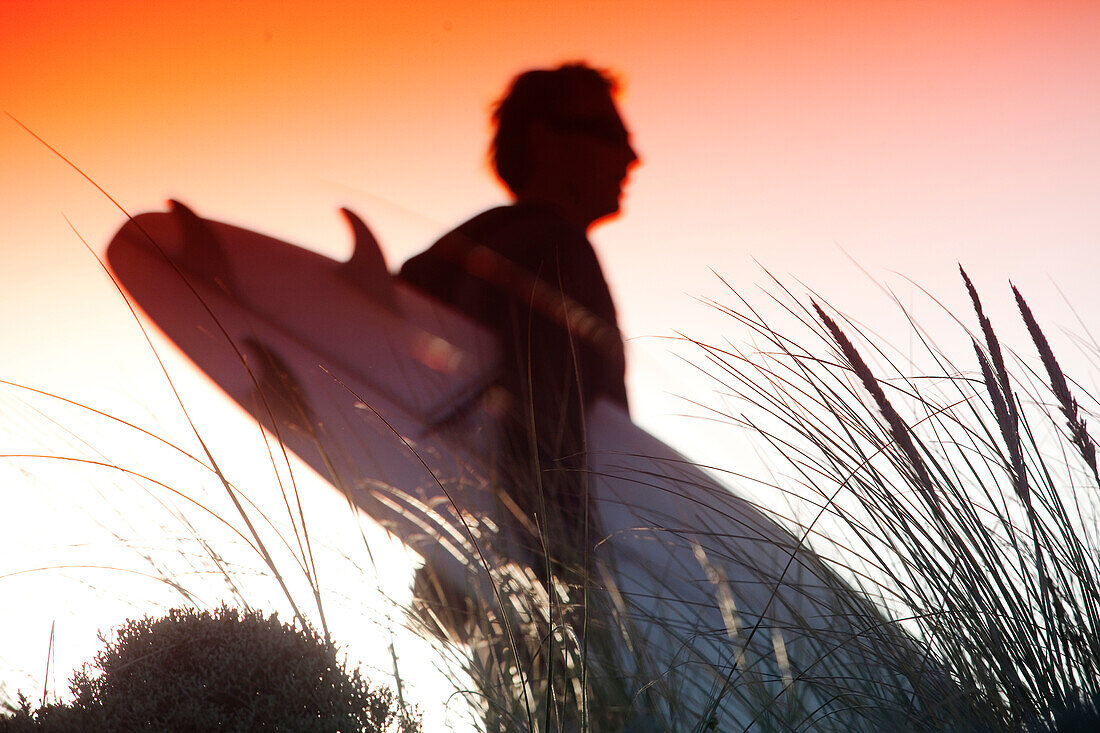 A surfer silhouetted against the rising sun, on King Island, in Tasmania, Australia King Island, Tasmania, Australia