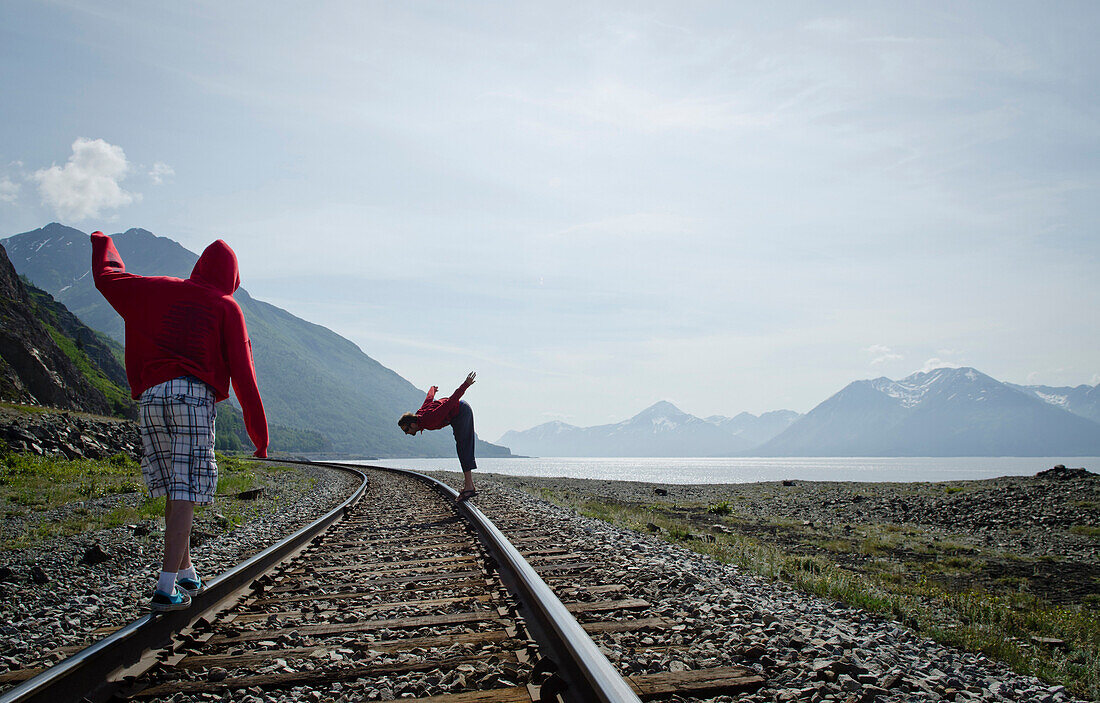 Two young men walk along a train track in Anchorage, Alaska Anchorage, Alaska, USA