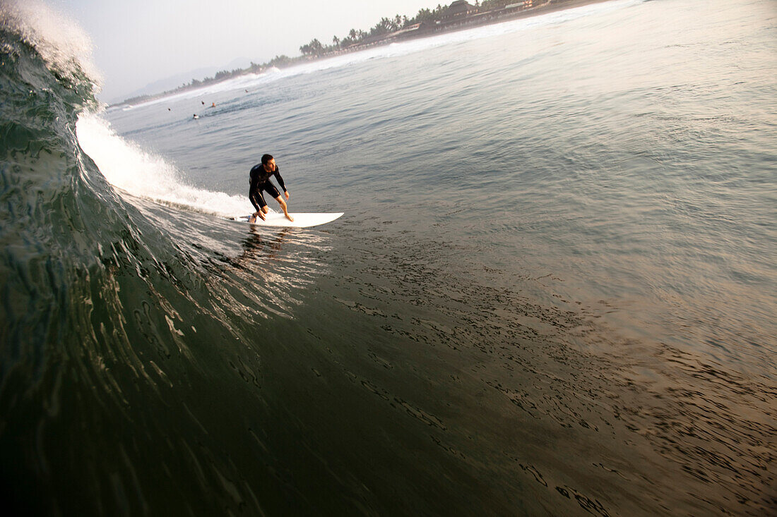 A male surfer wearing a spring suit leans into a bottom turn while surfing the notorious beach break of Pasquales, Mexico on May Pasquales, Colima, Mexico