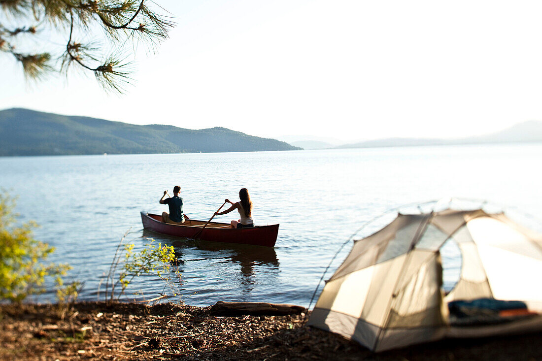 Two young adults canoeing on a camping trip next to a lake in Idaho Sandpoint, Idaho, USA