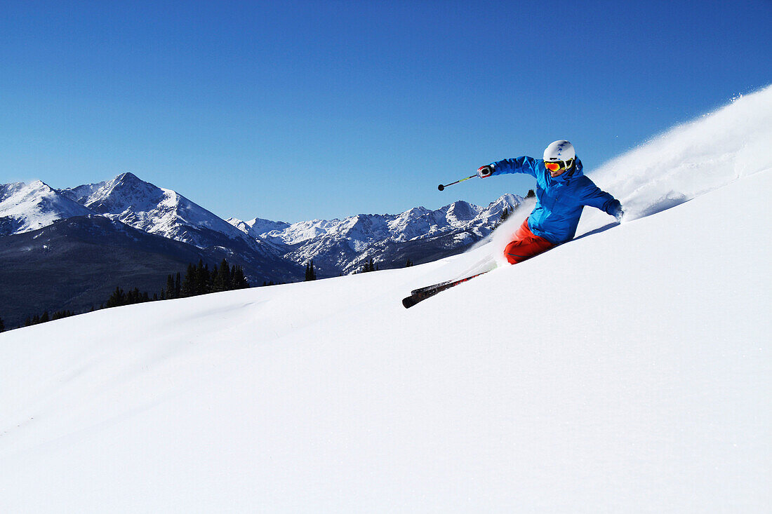 A athletic skier rips fresh powder turns on a sunny day in Colorado Vail, Colorado, USA
