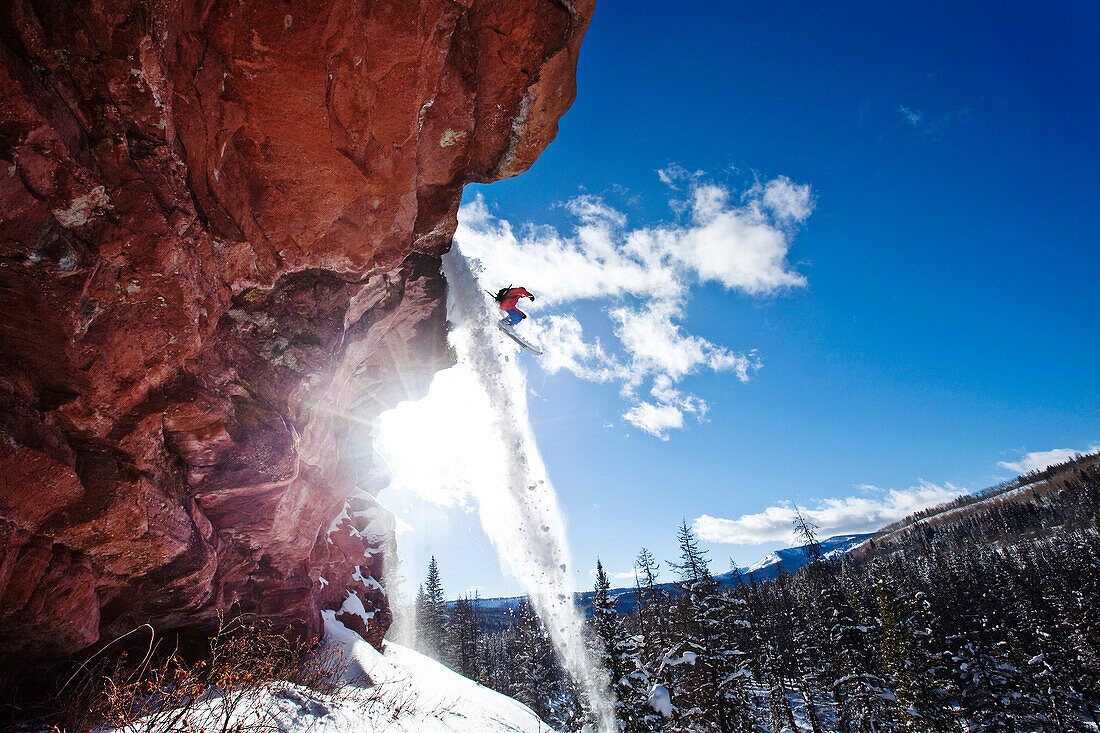 A athletic skier jumping off a cliff in the backcountry on a sunny day in Colorado Vail, Colorado, USA