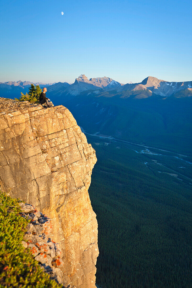 A hiker sits on a cliff edge, Banff National Park, Alberta, Canada Alberta, Canada