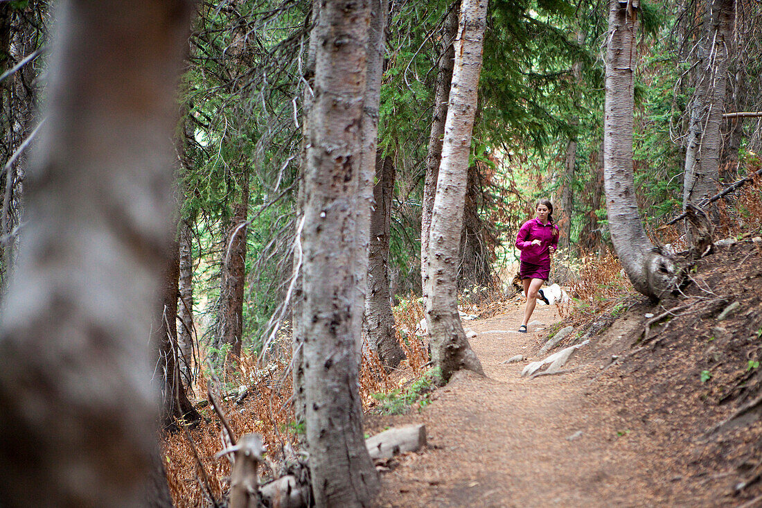 A woman trail running through the woods of Solitude ski resort