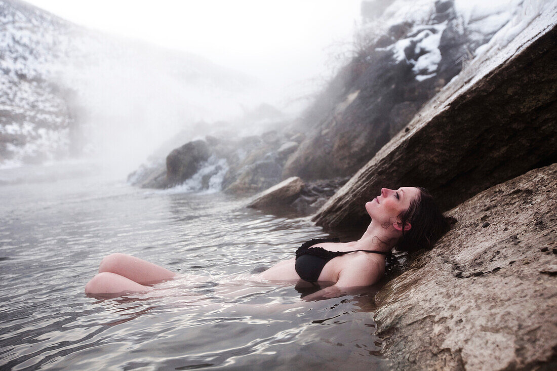 A beautiful woman relaxing in a hot springs waterfall in Montana., Bozeman, Montana, USA