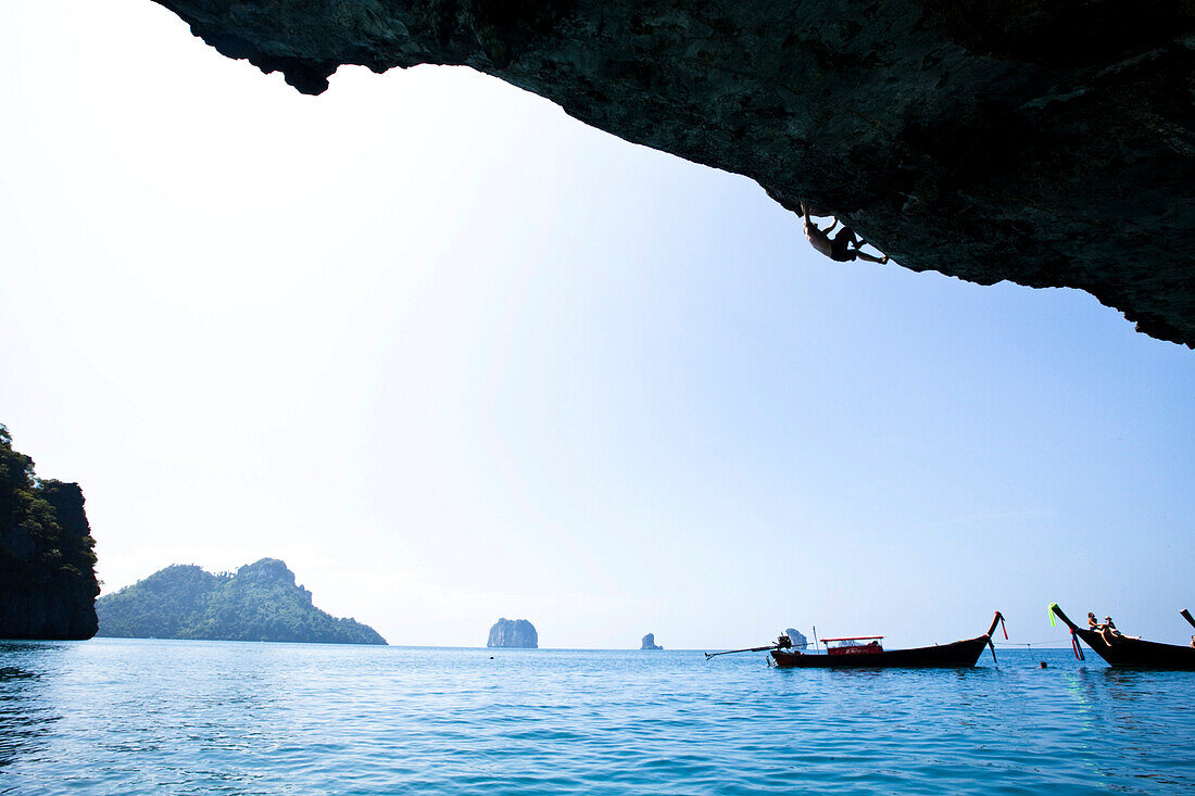 A athletic man deep water soloing, rock climbing with out ropes in Thailand., Railay, Thailand