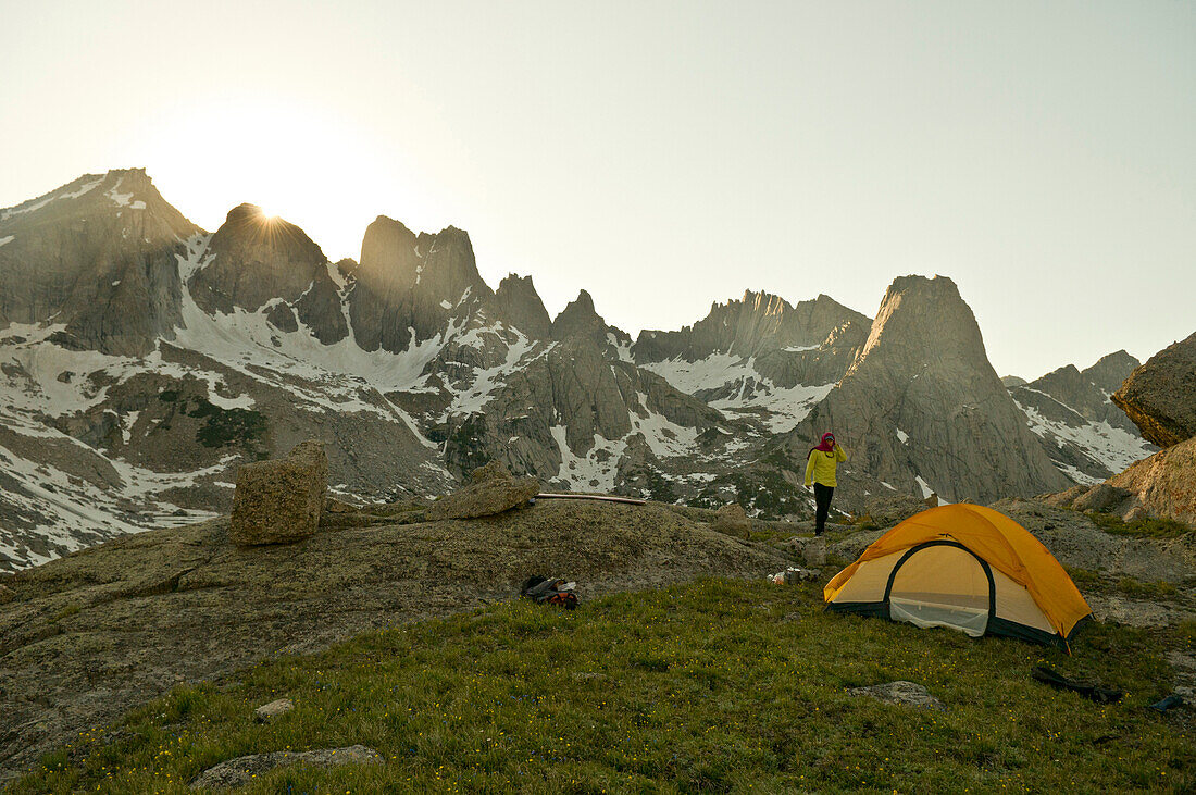 A woman standing next to tent at sunset, Cirque of Towers, Wind River Range, Pinedale, Wyoming., Pinedale, Wyoming, usa