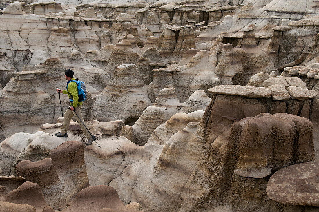 A man hiking through the complex sandstone rock formations at Bisti Badlands, Farmington, New Mexico., Farmington, New Mexico, usa