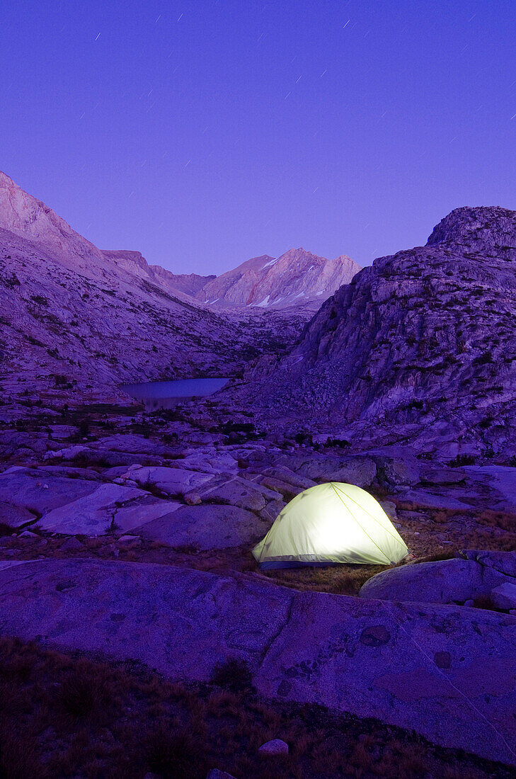 A tent is illuminated at dusk near Cirque Pass on the Sierra High Route, CA., The Sierra High Route, California, USA