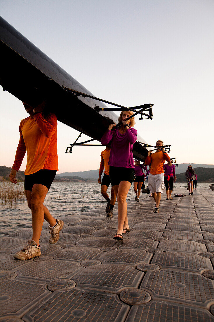 Men and women of the Lake Casitas Rowing Team carry their boat up a dock at Lake Casitas in Ojai, California., Ojai, California, United States of America