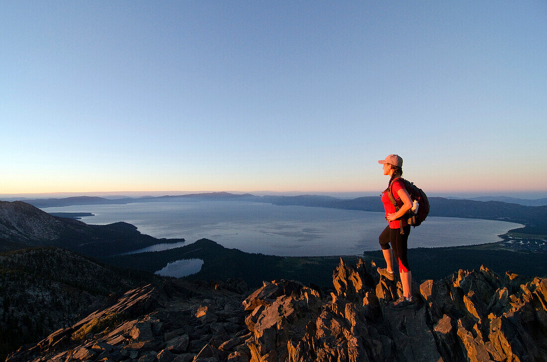 A female hiker enjoys a spectacular view of Lake Tahoe at sunset from the summit of Mount Tallac, CA., Lake Tahoe, California, USA