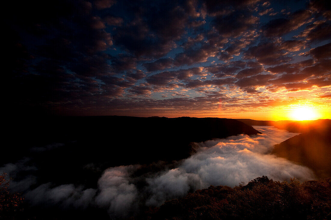 Colorful clouds and fog over a river in a gorge at sunrise., Fayetteville, WV, USA