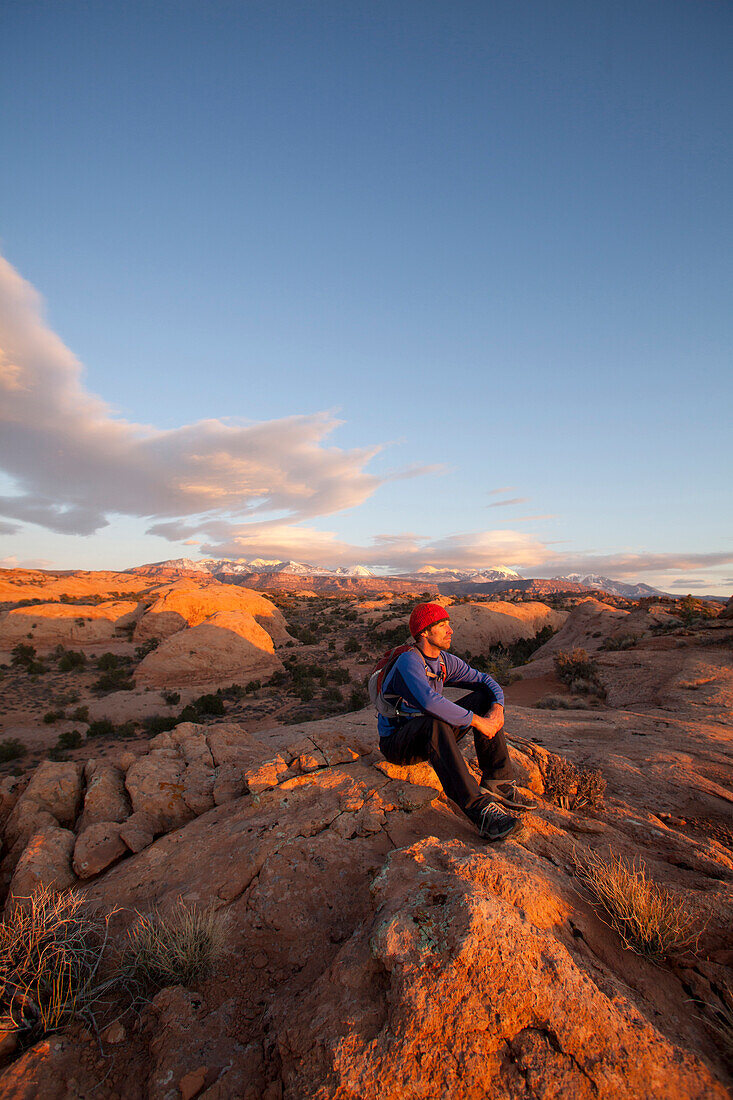 Young man hiking on slickrock near Moab, Utah., Moab, Utah, USA