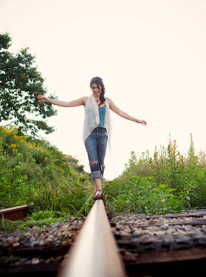 A young woman balances on a railroad track in the summer., Portland, ME, USA