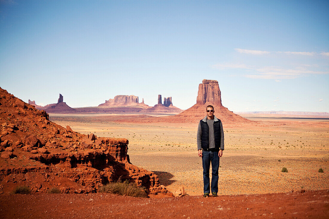 A man poses for a picture among the rock formations of Monument Valley on the Utah/Arizona border., Kayenta, AZ, USA