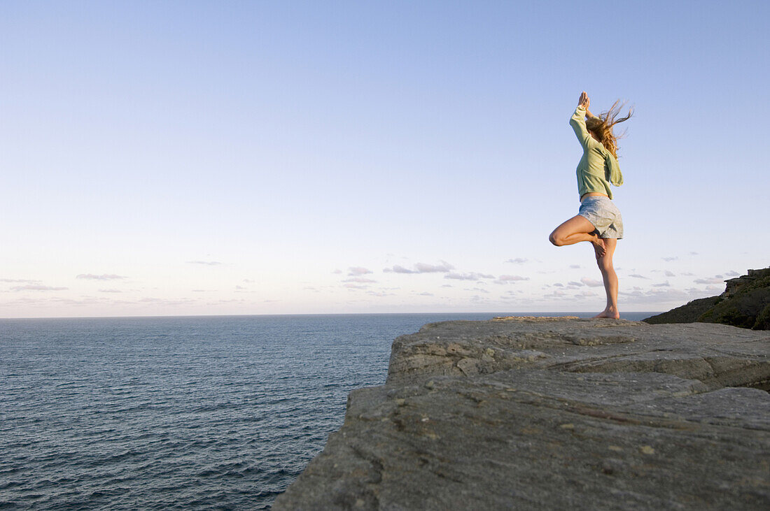 Yoga on rocky outcrop above ocean Sydney, New South Wales, Australia