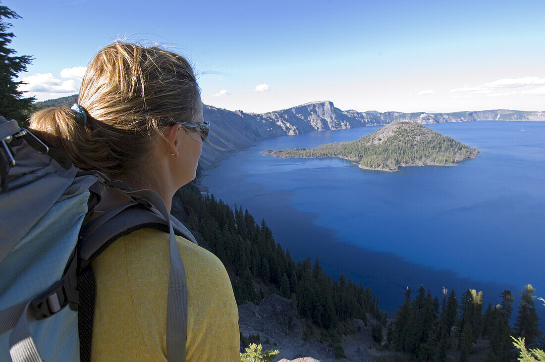Hiker along cliff trail near lake Crater Lakes National Park, Oregon, United States