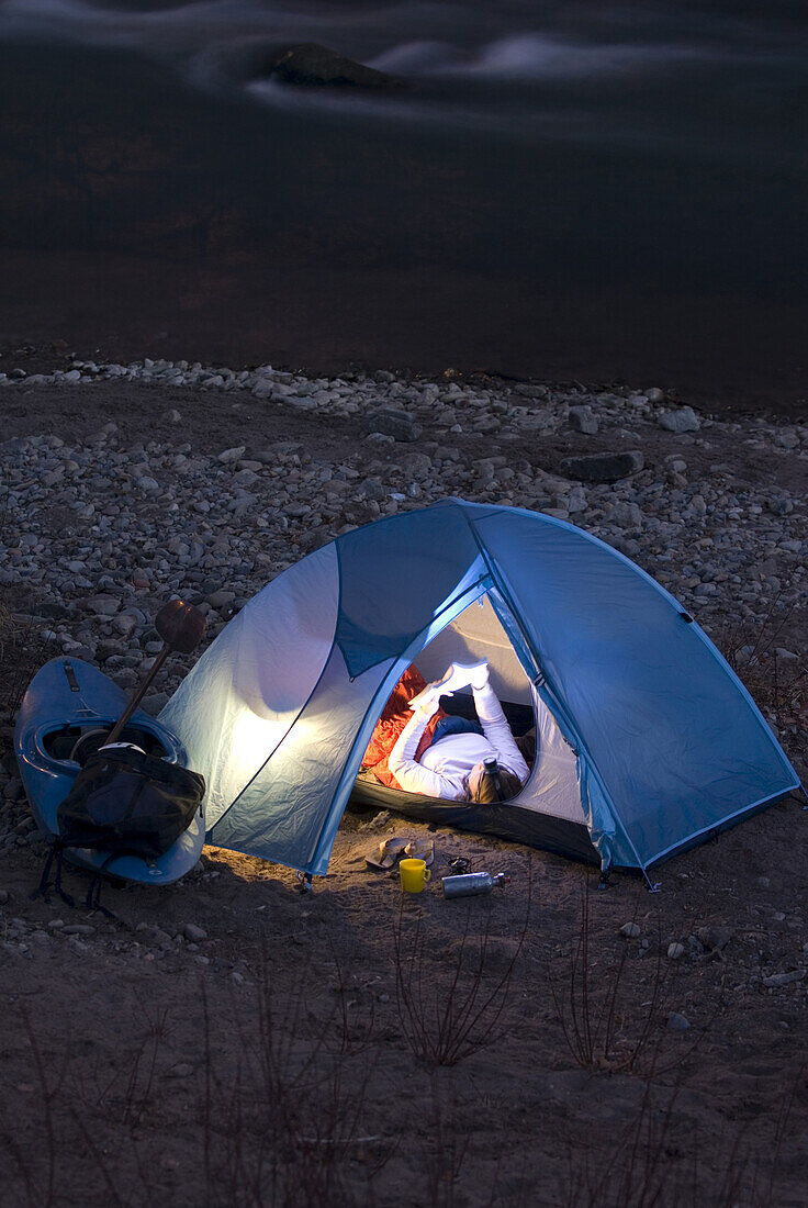 Woman camps in tent by a river Durango, Colorado, United States