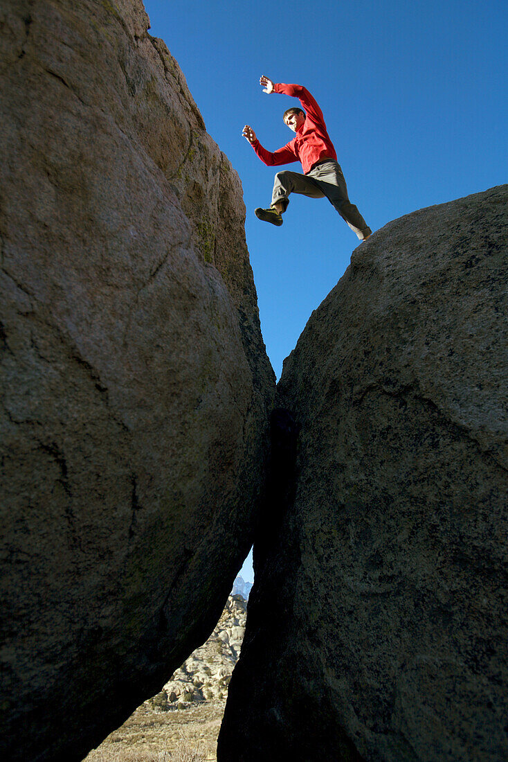 Man jumping across boulders, Bishop, California, United States
