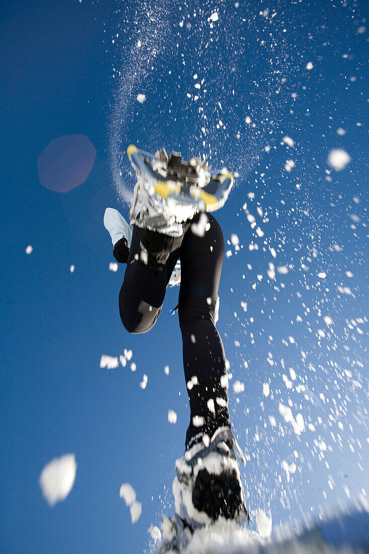 woman jumps overhead in snowshoes