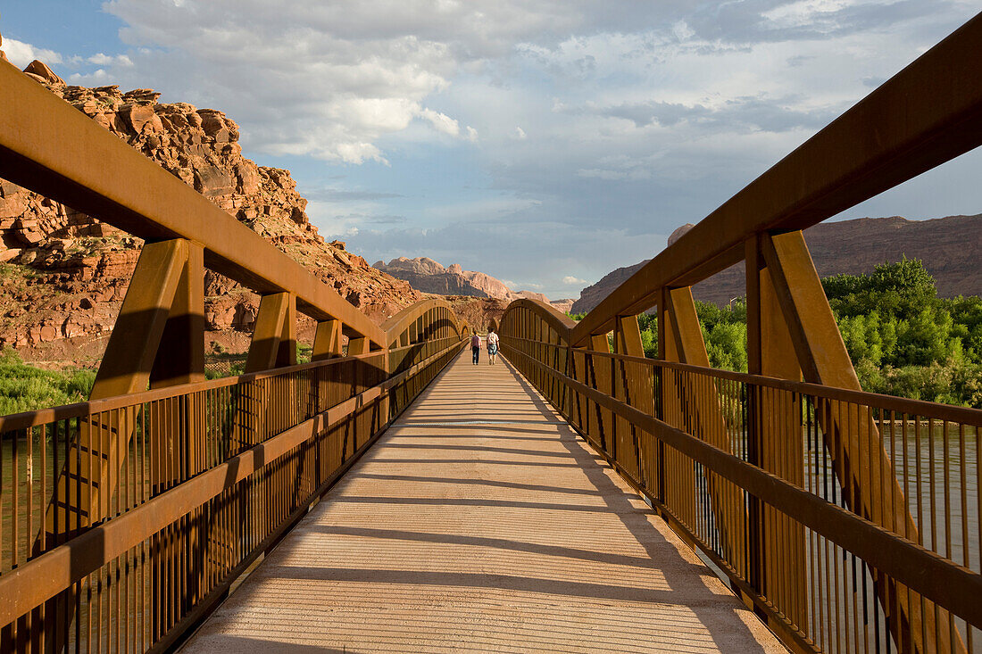 Two people in distance walking across bridge in Moab, Utah Moab, Utah, USA