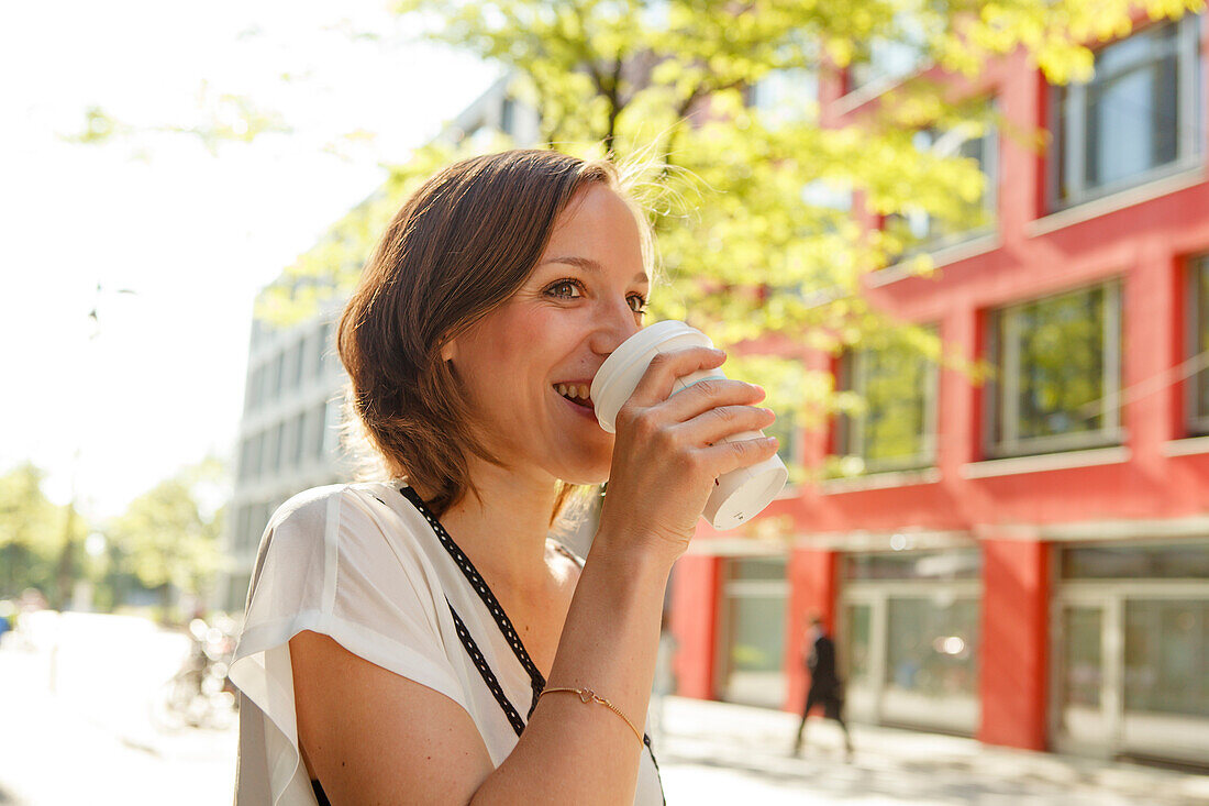 Frau trinkt aus einem Kaffeebecher, München, Bayern, Deutschland