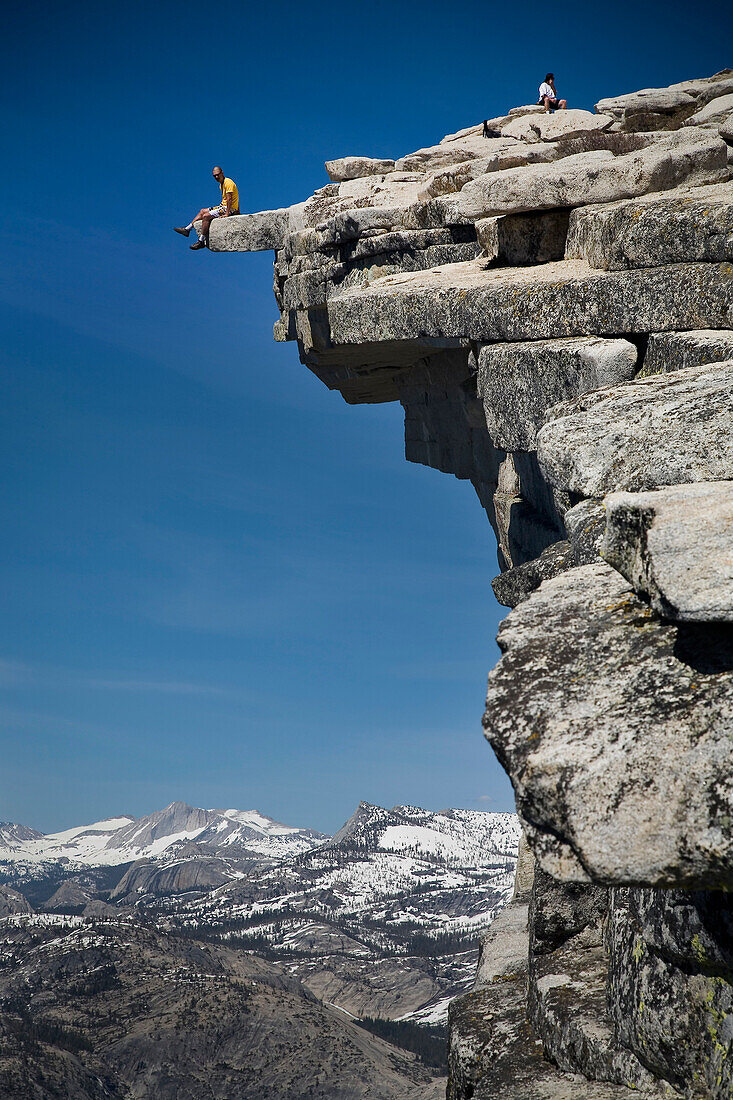 'Climber sits on the edge of ''The Diving Board'' atop Half Dome in the Yosemite Valley Yosemite Valley, California, USA'