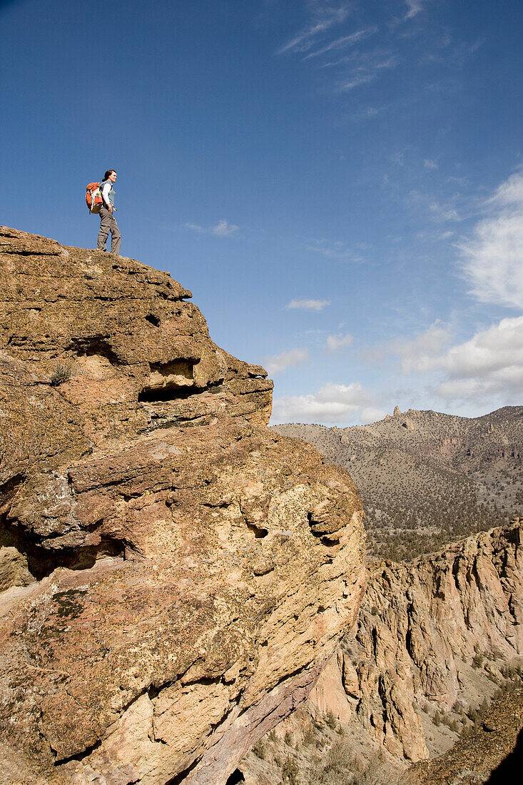 A woman with a day pack overlooking a river flowing through beautiful cliffs Terrebone, Oregon, USA