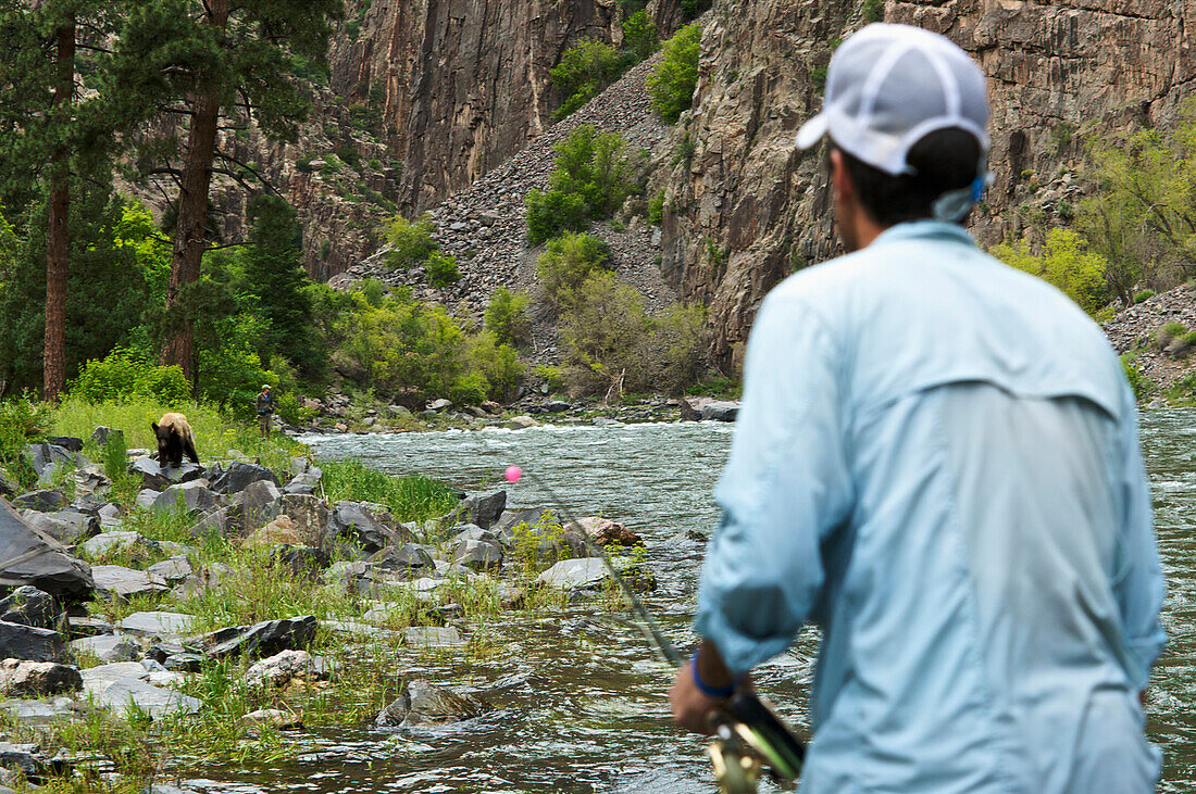 Two fisherman watch a bear carefully in Black Canyon National Park Gunnison, Colorado, USA