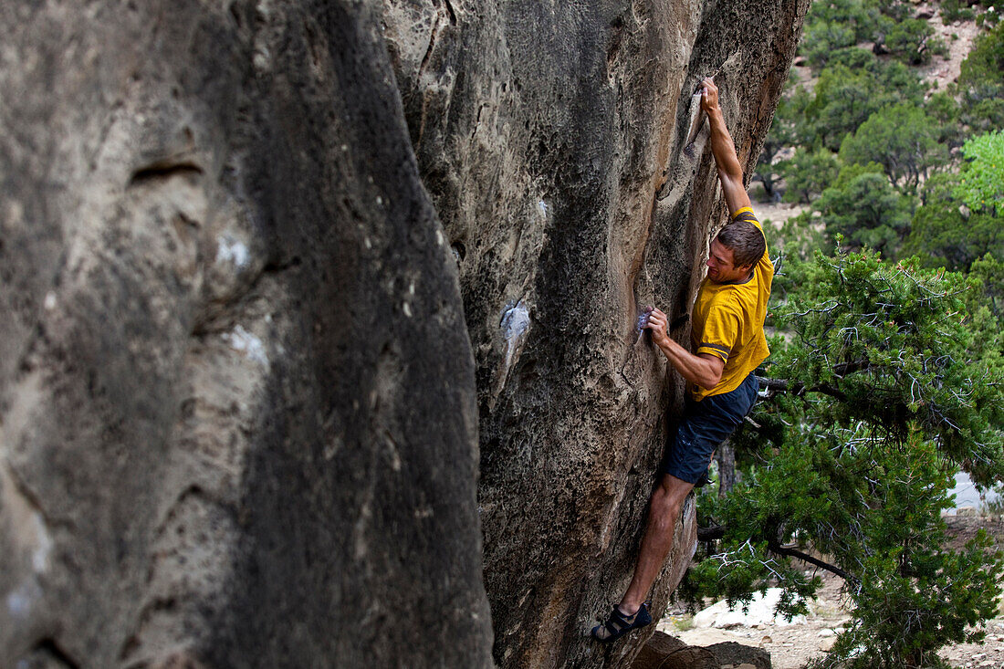 A man crimps hard while stretched out on a boulder problem at Joes Valley Utah Aurora, Colorado, USA