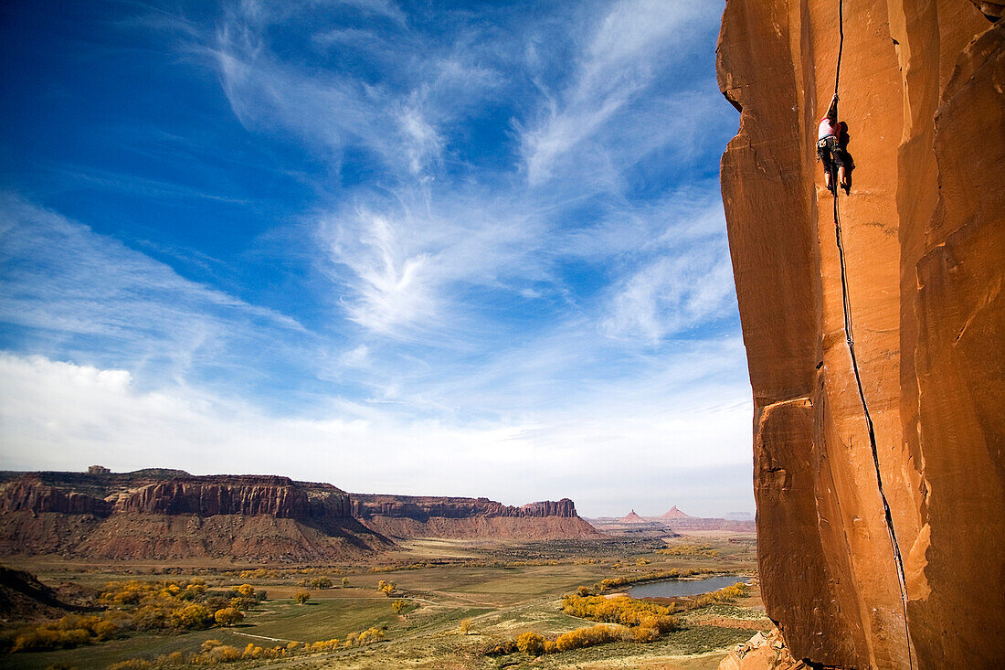 A female rock climber climbs the classic route called Scarface, rated 5.11a, in Indian Creek, Utah Indian Creek, Utah, USA
