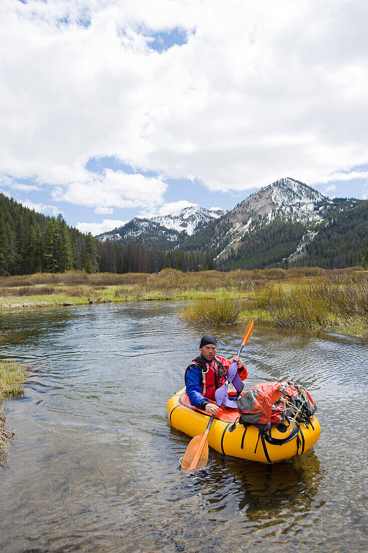 A young man paddles his small, inflatable raft on the upper reaches of the Salmon River in Idaho Idaho, USA