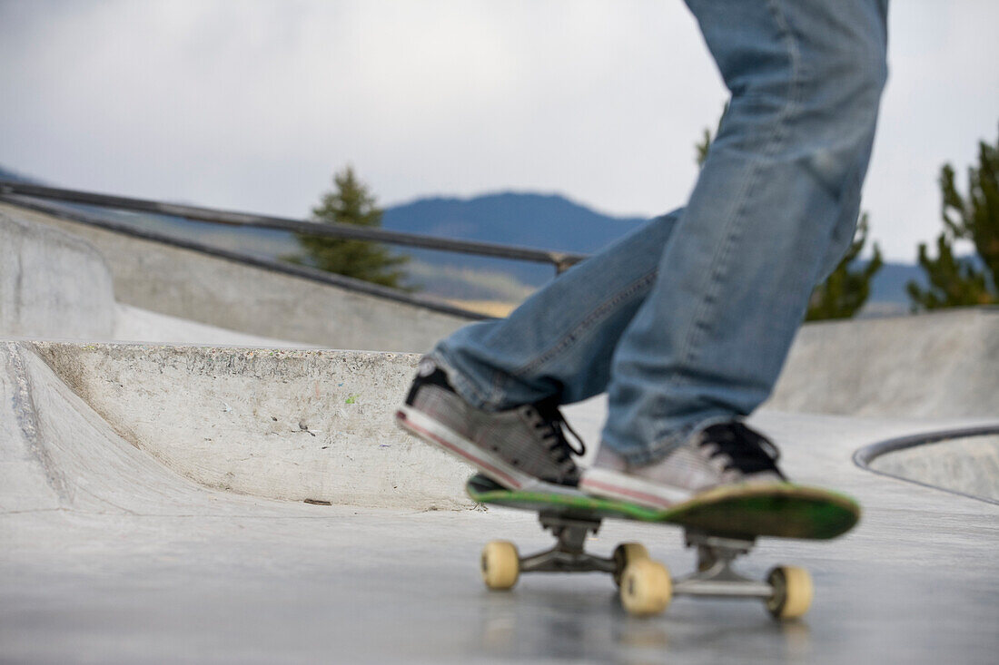 Teenage male skateboarding at a paved public skate park Whitefish, Montana, USA