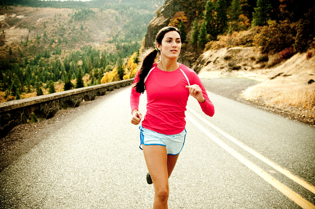 An athletic woman jogging along a deserted road on a beautiful fall day Hood River, Oregon, USA