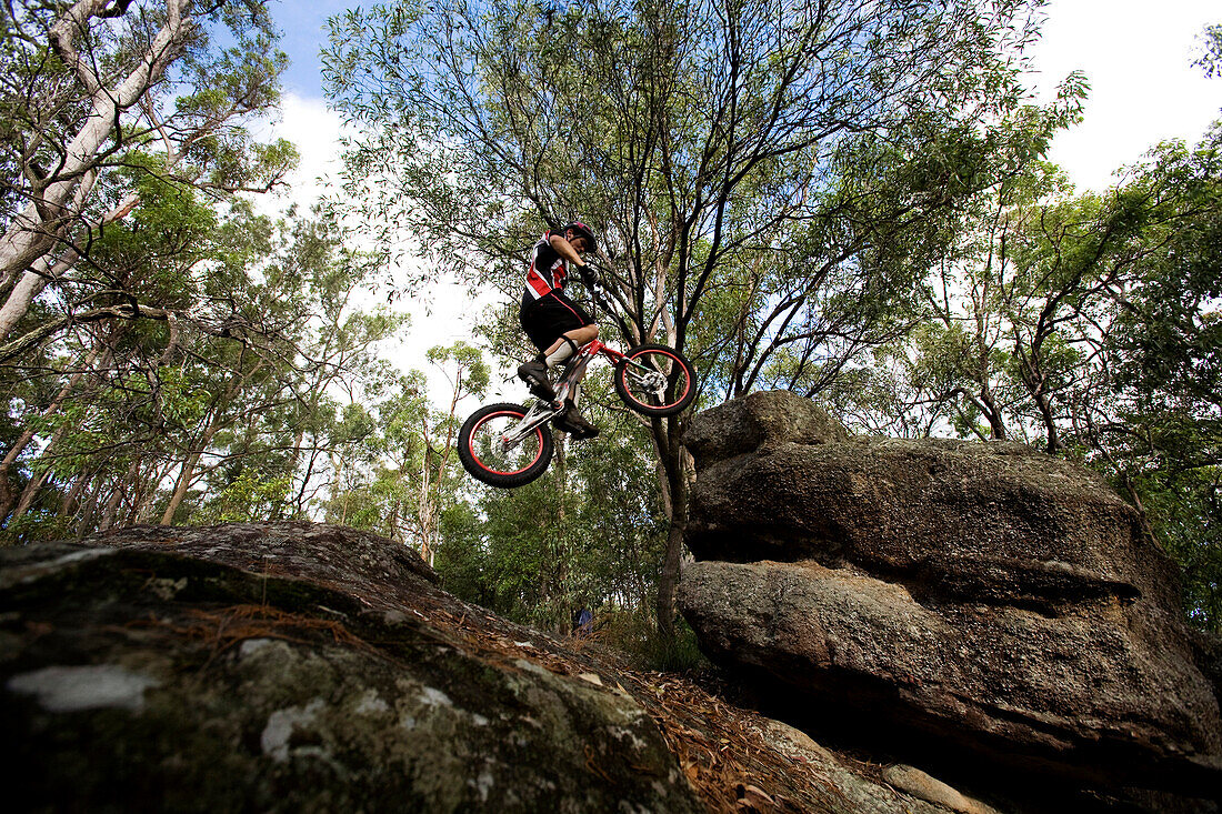A Trials rider leaps onto a rock at Toohey Forest, Brisbane, Queensland, Australia Brisbane, Queensland, Australia