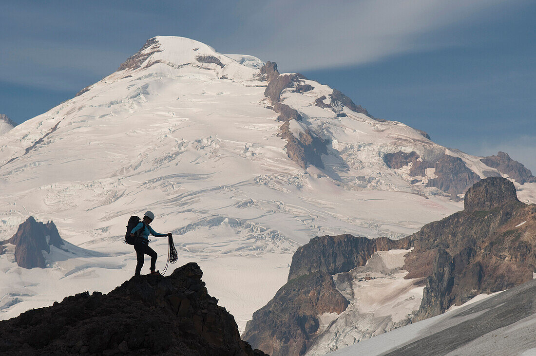 A woman mountaineer standing on pinnacle below Mount Baker, Mount Baker Wilderness, Bellingham, Washington Bellingham, Washington, USA