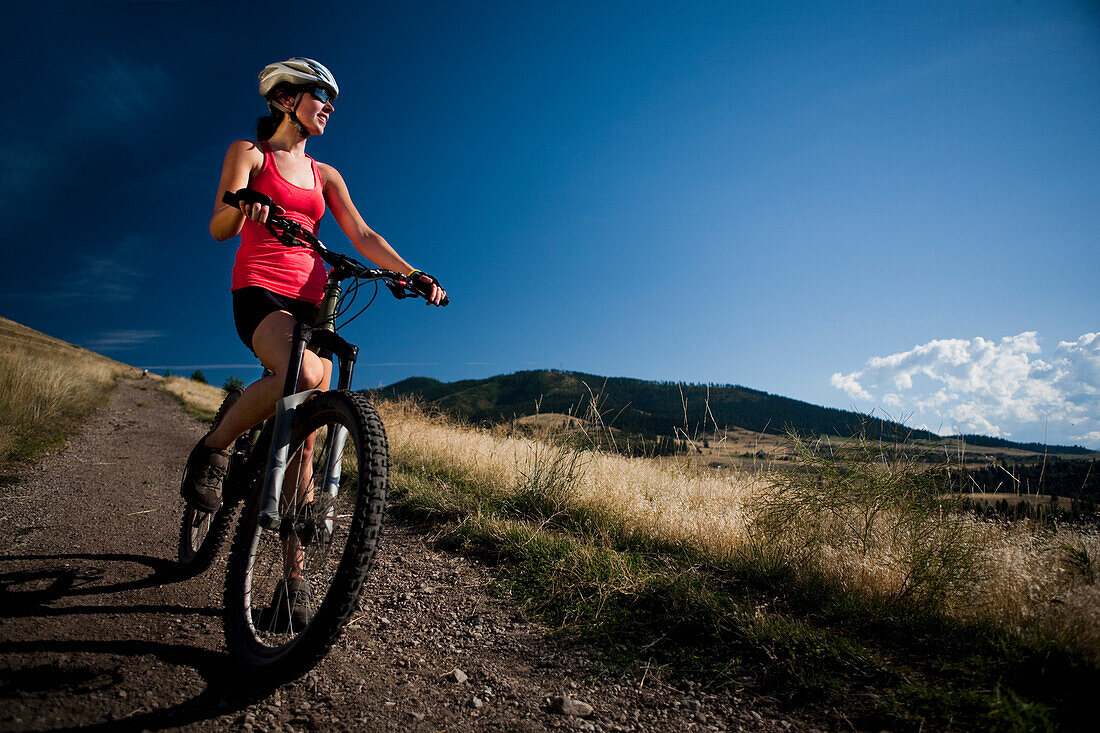 A female mountain biker stops to enjoy the view while riding the trails of Mt. Sentinel, Missoula, Montana Missoula, Montana, USA