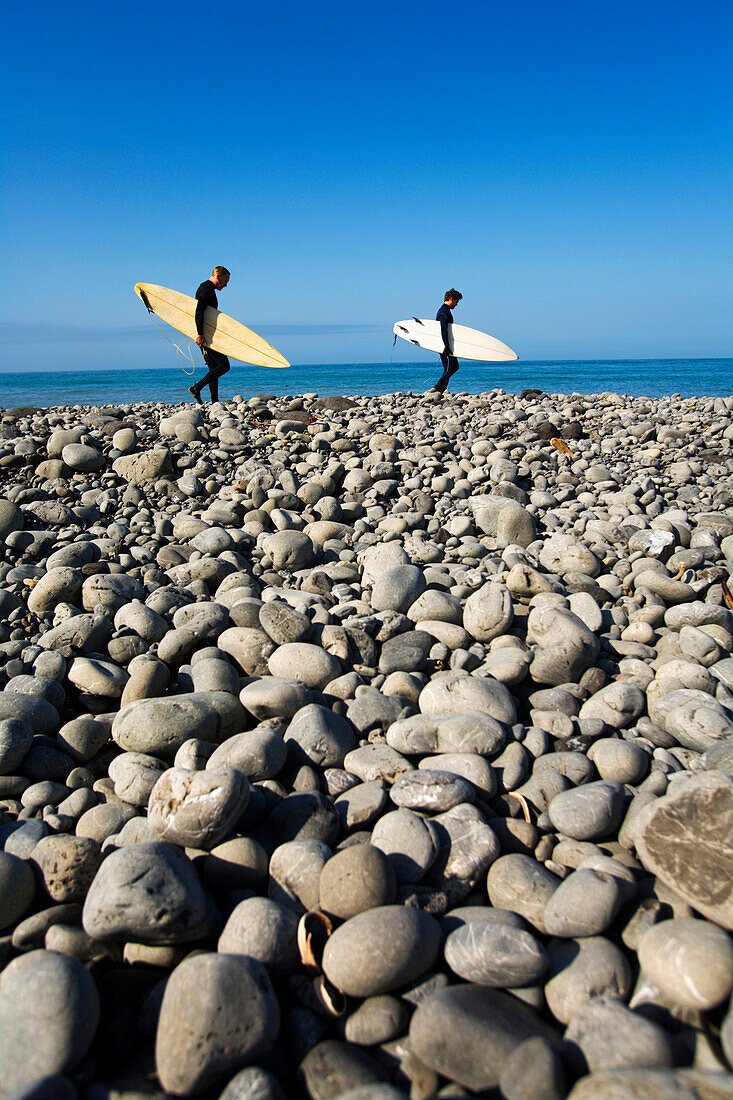 Two men walk the beach with surfboards under their arms on The Lost Coast, California Shelter Cove, California, USA