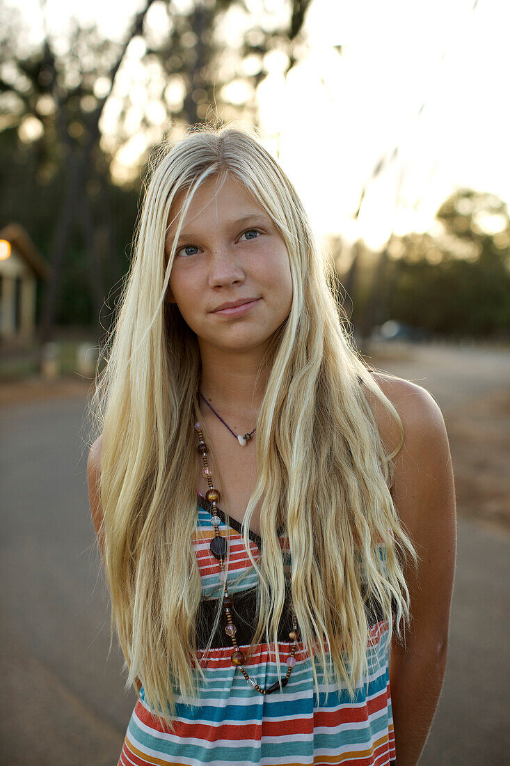 A pre-teen girl with long blond hair poses for the camera in Maui, Hawaii on an early morning at Paia Beach Maui, Hawaii, USA