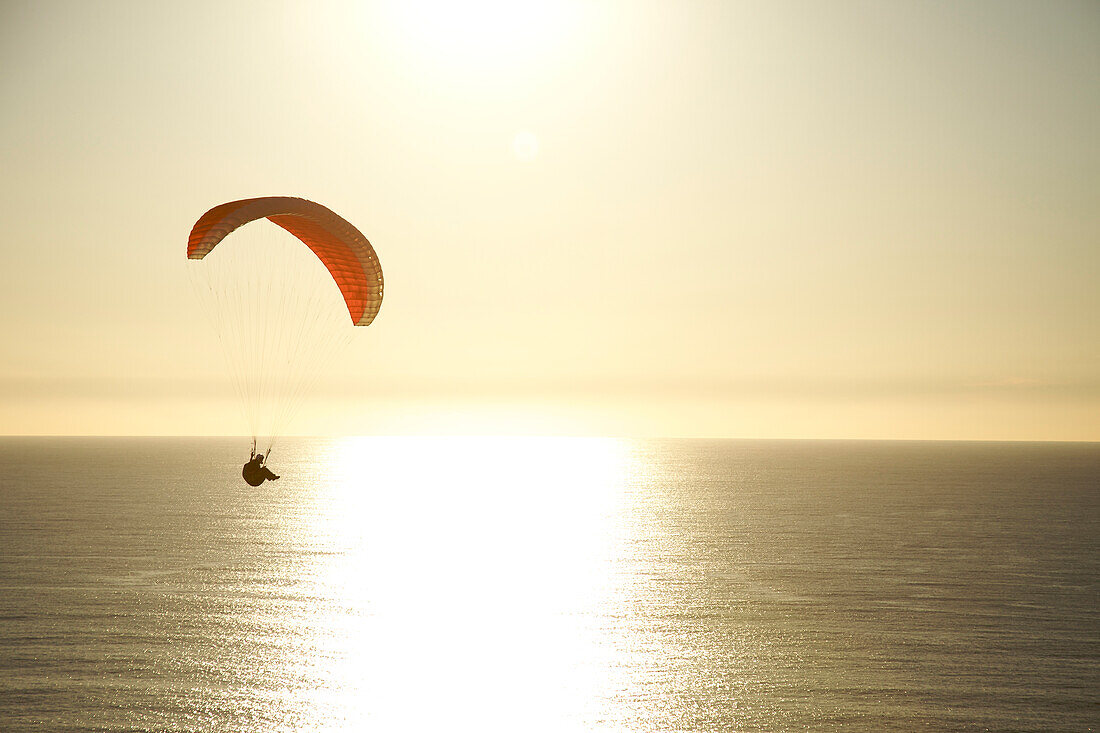Paraglider rides the wind at sunset over the ocean in California San Diego, California, USA